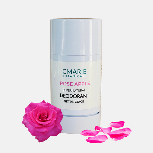 Image of CMarie Botanicals Rose Apple Supernatural Deodorant, a natural deodorant in a sleek white 2.30 oz container. The product is accompanied by fresh, pink flowers and petals, emphasizing its natural rose fragrance.