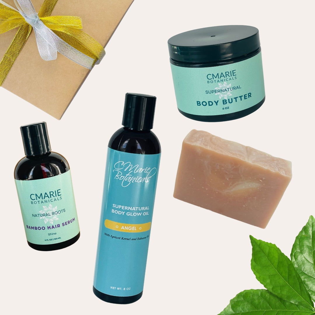 "Gift box featuring four natural products: Bamboo Hair Serum, Angel Body Glow Oil, Supernatural Body Butter, and a handcrafted bar of natural soap. The products are arranged next to a brown gift box tied with a yellow ribbon and a green leaf accent."